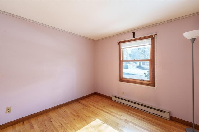 empty room featuring a baseboard heating unit, light wood-type flooring, and baseboards