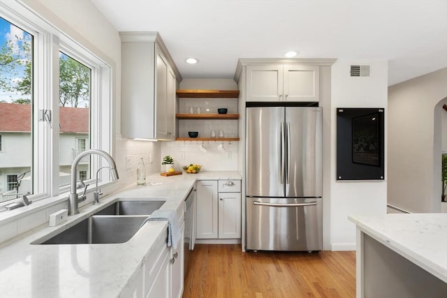 11 Williams St, Arlington, MA 02476 - kitchen featuring stainless steel appliances, light wood-style floors, backsplash, open shelves, and light stone countertops