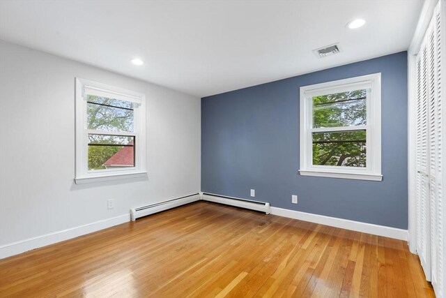 11 Williams St, Arlington, MA 02476 - unfurnished bedroom featuring a baseboard radiator, hardwood / wood-style floors, multiple windows, and recessed lighting