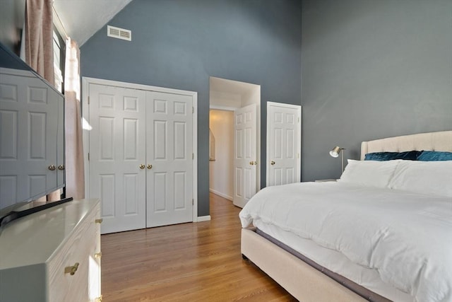 bedroom featuring visible vents, high vaulted ceiling, light wood-type flooring, and baseboards