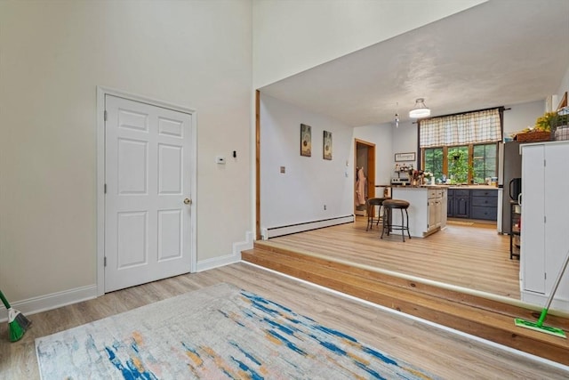 161 Old Farm Rd, Leominster, MA 01453 - living room with a baseboard radiator, light wood-style floors, baseboards, and a towering ceiling