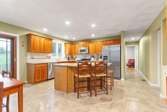 19 Miele Rd, Marlborough, MA 01752 - kitchen with appliances with stainless steel finishes, a kitchen island, a sink, a kitchen bar, and decorative backsplash