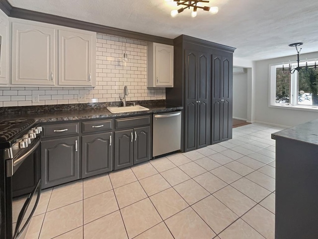 kitchen featuring light tile patterned floors, decorative backsplash, dark countertops, stainless steel appliances, and a sink