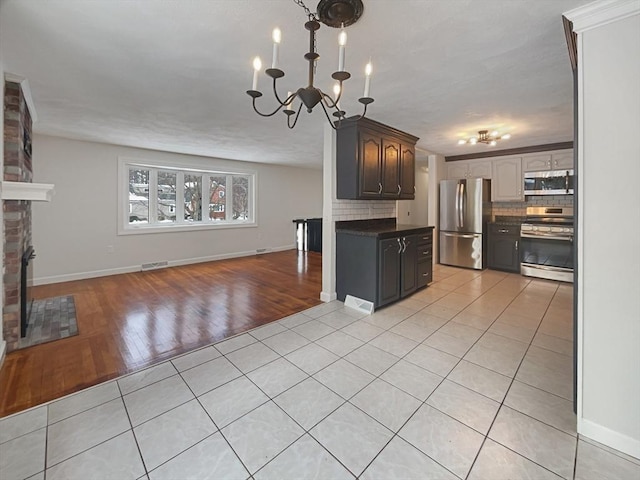 kitchen with light tile patterned floors, open floor plan, appliances with stainless steel finishes, tasteful backsplash, and dark countertops