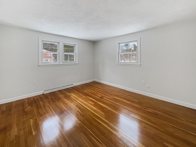 spare room with hardwood / wood-style flooring, a baseboard radiator, baseboards, and a textured ceiling