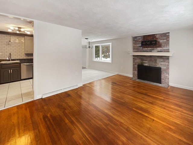 unfurnished living room featuring light wood-type flooring, a fireplace, baseboards, and a sink