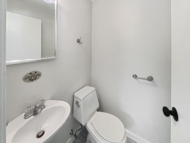 bathroom with toilet, baseboards, and a sink