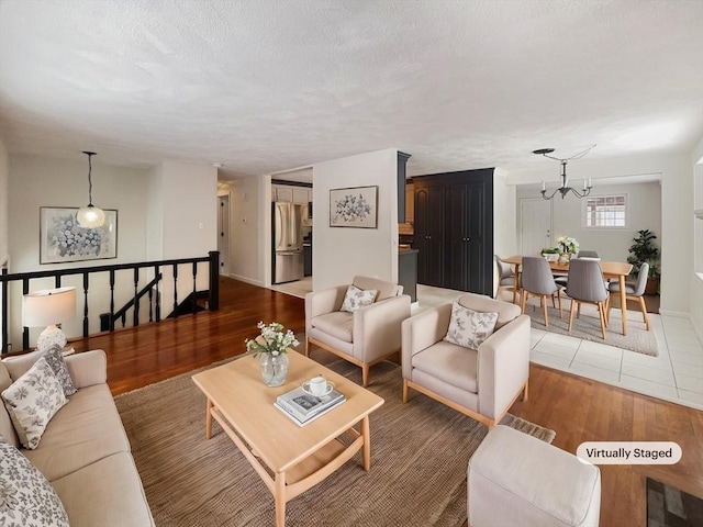 living room with a textured ceiling, baseboards, wood finished floors, and an inviting chandelier