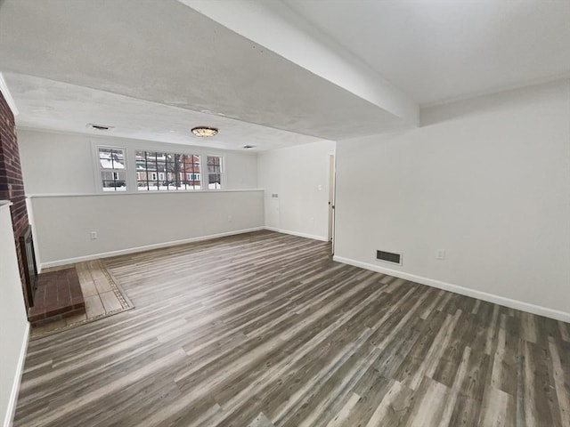 unfurnished living room featuring visible vents, a fireplace, baseboards, and wood finished floors