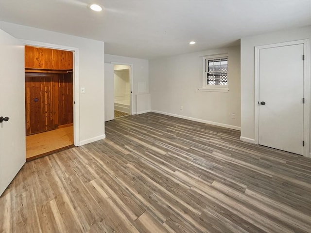 unfurnished bedroom with baseboards, wood finished floors, connected bathroom, and recessed lighting