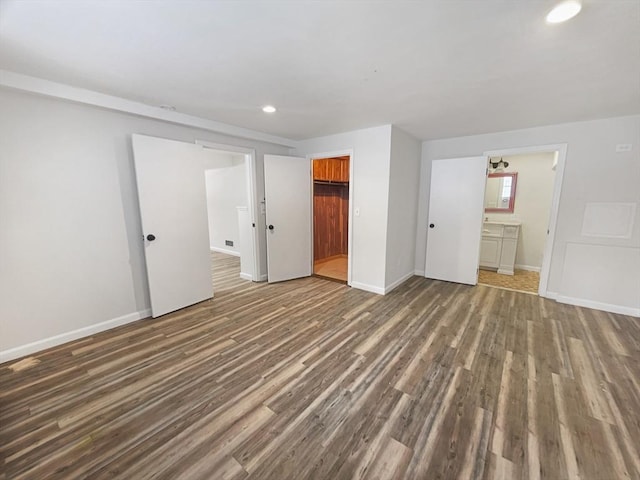 unfurnished bedroom with baseboards, wood finished floors, ensuite bathroom, a closet, and recessed lighting