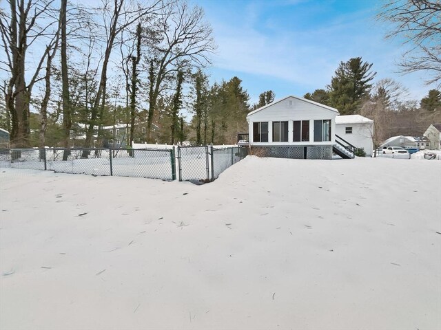 yard layered in snow featuring a gate, fence, and a sunroom