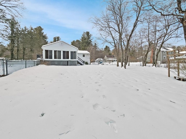 yard covered in snow featuring a sunroom and fence