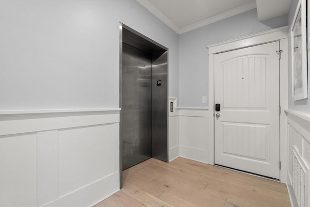 entryway featuring visible vents, light wood-style flooring, ornamental molding, elevator, and wainscoting