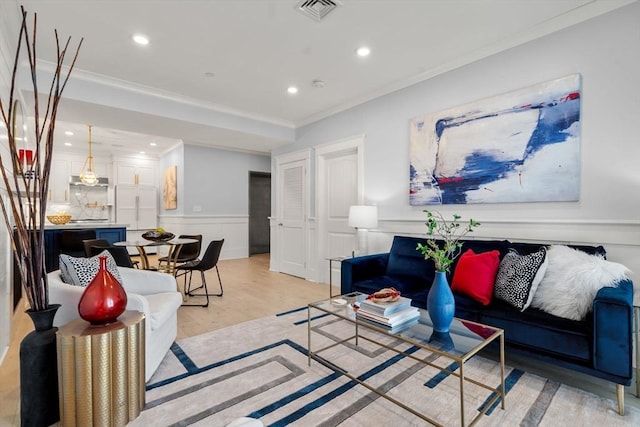 living room with recessed lighting, visible vents, light wood-type flooring, wainscoting, and crown molding