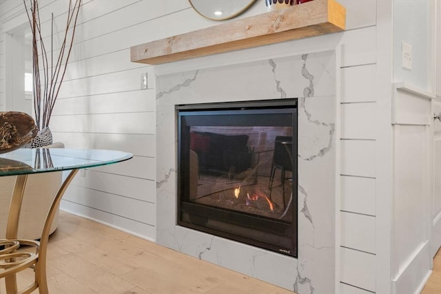 details with wood finished floors, a high end fireplace, and wooden walls