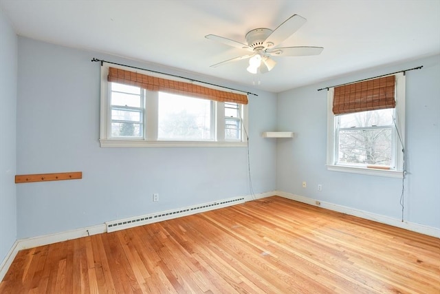 empty room featuring baseboards, a ceiling fan, a baseboard heating unit, and wood finished floors