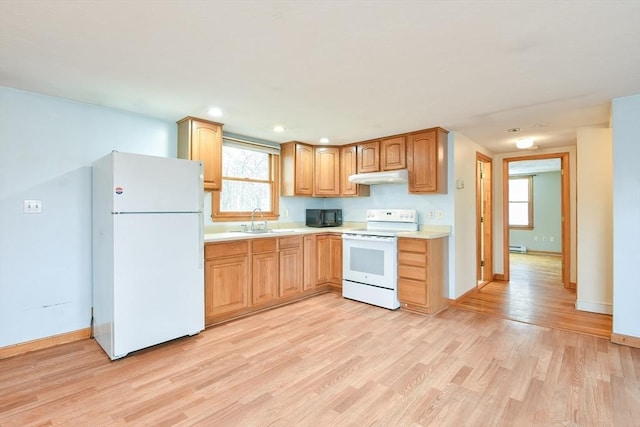 kitchen with white appliances, under cabinet range hood, light countertops, a sink, and light wood finished floors