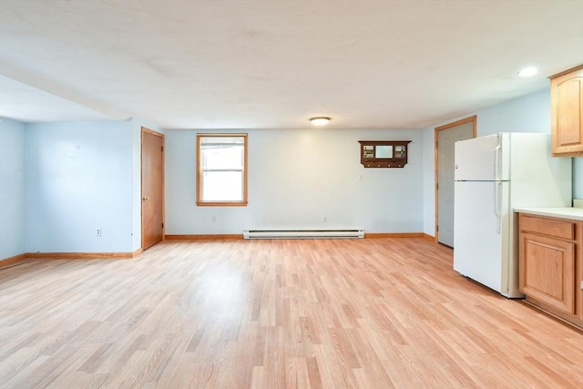 interior space with baseboards, light wood finished floors, a baseboard radiator, and freestanding refrigerator