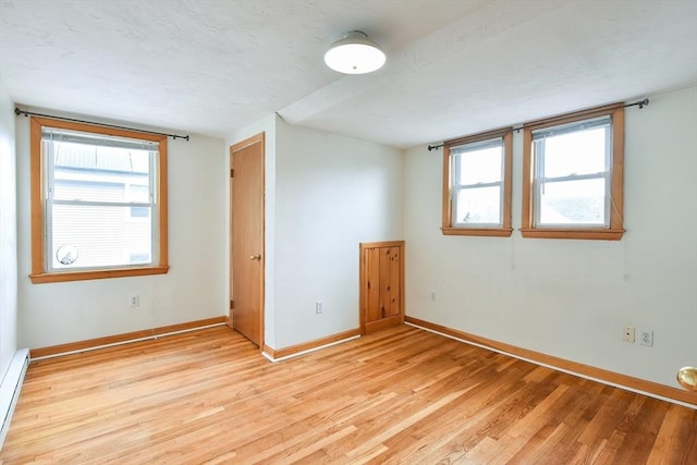 empty room with baseboards, light wood-style floors, and baseboard heating