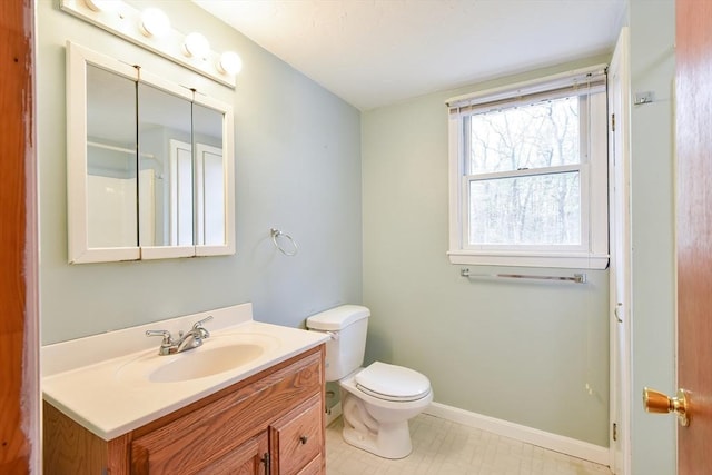 bathroom with toilet, vanity, and baseboards