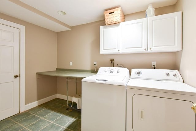 washroom featuring dark tile patterned flooring, baseboards, washing machine and clothes dryer, and cabinet space