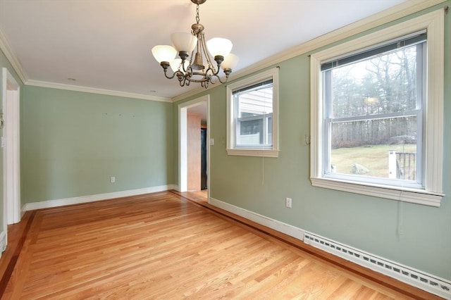 empty room featuring a notable chandelier, a baseboard heating unit, ornamental molding, and light wood-style flooring