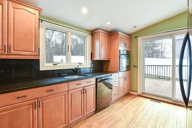 kitchen with black dishwasher, a sink, wall oven, dark stone counters, and lofted ceiling