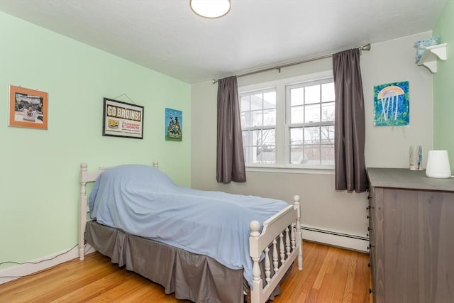 bedroom featuring a baseboard heating unit and light wood-style flooring