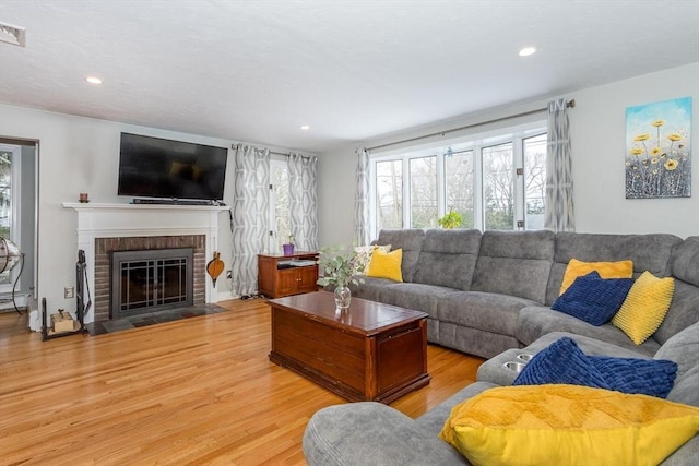 living area featuring recessed lighting, a fireplace, and wood finished floors