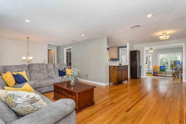 living area featuring recessed lighting, baseboards, visible vents, light wood-type flooring, and ceiling fan with notable chandelier