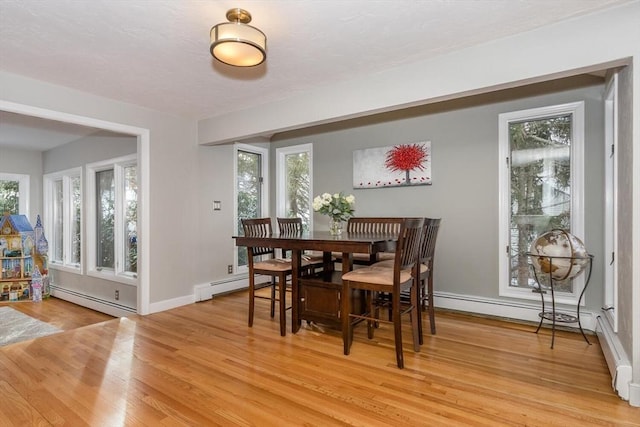 dining area with a baseboard heating unit, light wood-type flooring, and a wealth of natural light