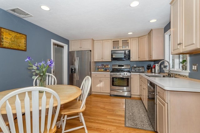 kitchen with visible vents, light wood-style flooring, appliances with stainless steel finishes, light countertops, and a sink