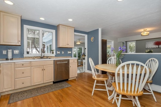 kitchen with a sink, baseboards, light countertops, stainless steel dishwasher, and light wood-type flooring