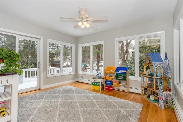 sunroom featuring a baseboard heating unit and ceiling fan