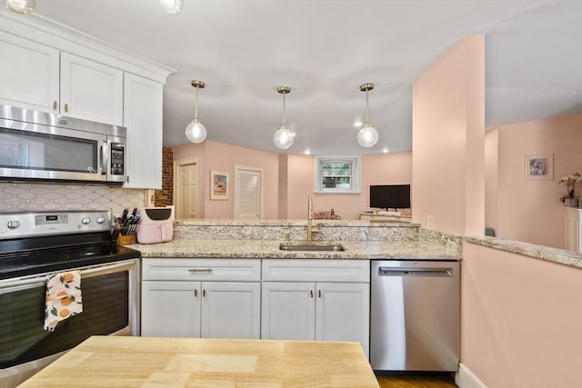 17 Gloucester St Unit A, Boston, MA 02115 - kitchen with stainless steel appliances, white cabinets, tasteful backsplash, light stone counters, and hanging light fixtures