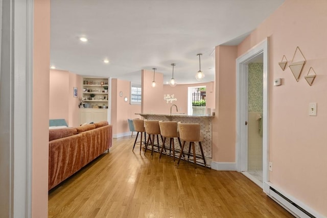 17 Gloucester St Unit A, Boston, MA 02115 - kitchen featuring a baseboard radiator, a breakfast bar, light wood-type flooring, a peninsula, and decorative light fixtures