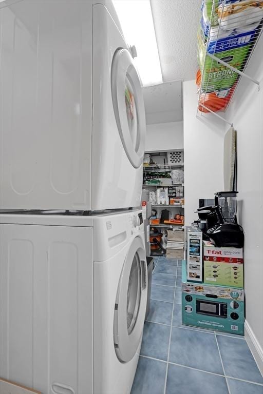 laundry area featuring laundry area, stacked washer and dryer, tile patterned floors, and a textured ceiling