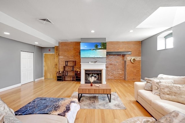 living area with wood finished floors, a fireplace, visible vents, and baseboards