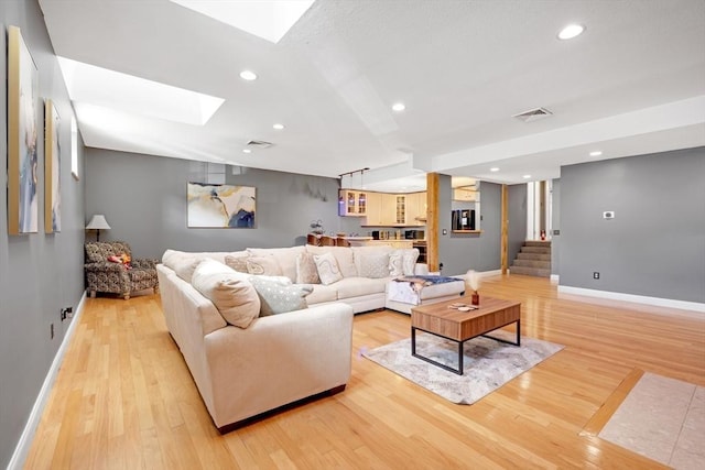 living area featuring light wood finished floors, visible vents, and a skylight