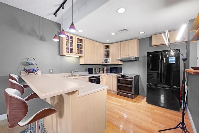 kitchen with visible vents, black appliances, under cabinet range hood, a sink, and a peninsula