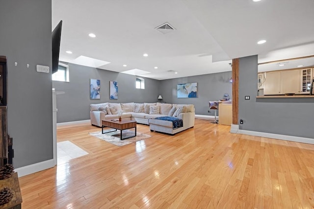 living room featuring recessed lighting, baseboards, and light wood-style flooring