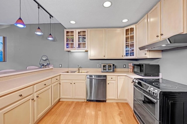 kitchen featuring under cabinet range hood, a sink, stainless steel appliances, light wood finished floors, and light countertops