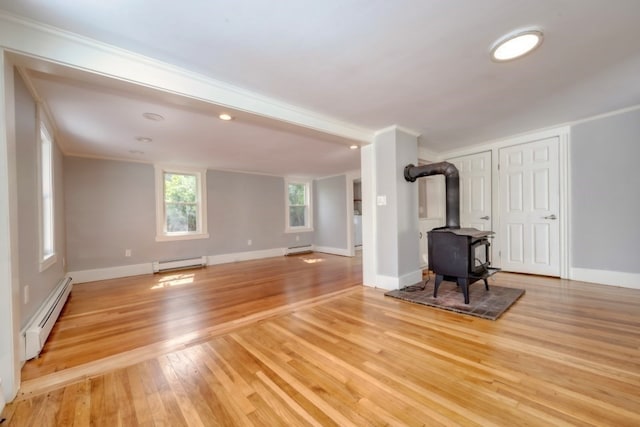 unfurnished living room with a wood stove, baseboard heating, and light wood-type flooring