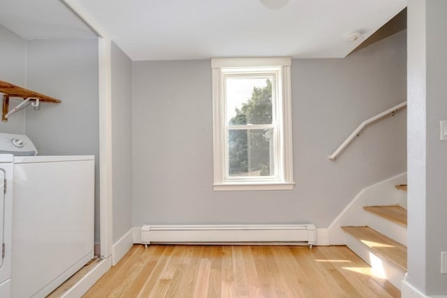 clothes washing area with separate washer and dryer, a baseboard radiator, and light hardwood / wood-style flooring