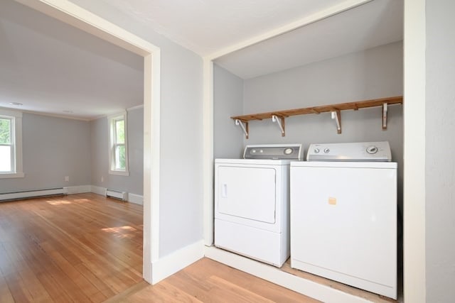 washroom with a baseboard radiator, light wood-type flooring, plenty of natural light, and washing machine and dryer