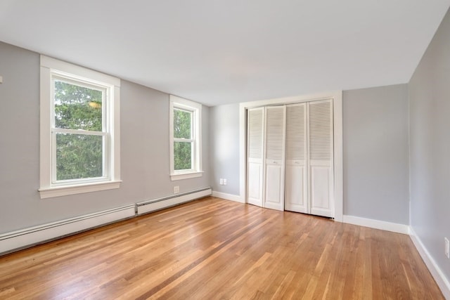 unfurnished bedroom with a baseboard radiator, light hardwood / wood-style flooring, and a closet