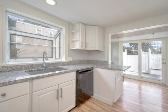 kitchen featuring white cabinets, black dishwasher, light wood-type flooring, and sink