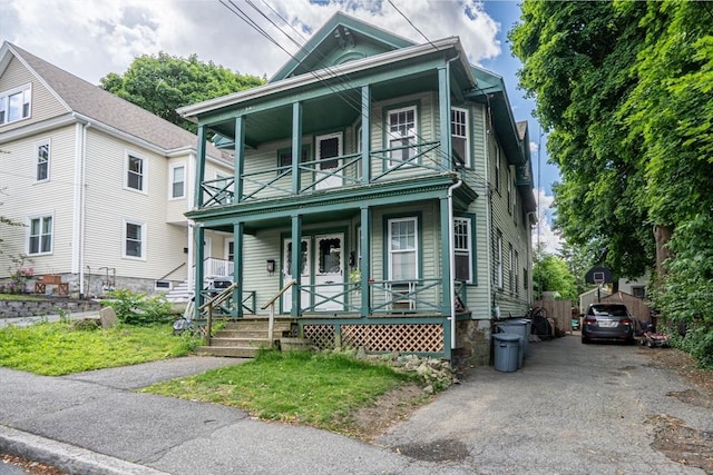 view of front of home featuring driveway, a balcony, and a porch