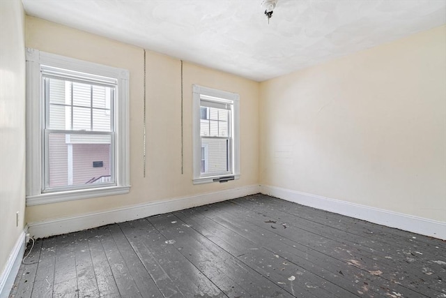 empty room with a healthy amount of sunlight, baseboards, and dark wood finished floors